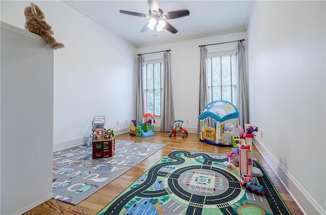 recreation room featuring hardwood / wood-style flooring, ceiling fan, and crown molding