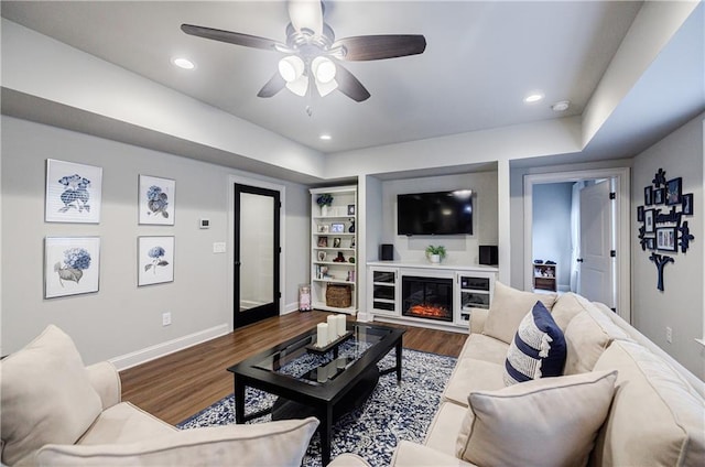 living room featuring hardwood / wood-style flooring, built in features, and ceiling fan