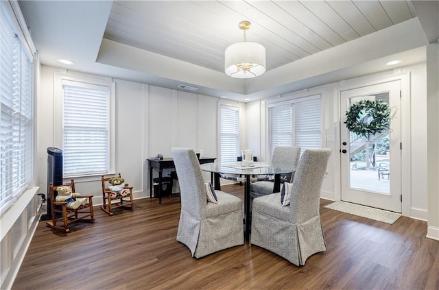 dining room featuring dark hardwood / wood-style flooring, a healthy amount of sunlight, a raised ceiling, and wood ceiling