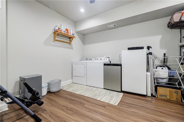 washroom with hardwood / wood-style floors and washing machine and dryer