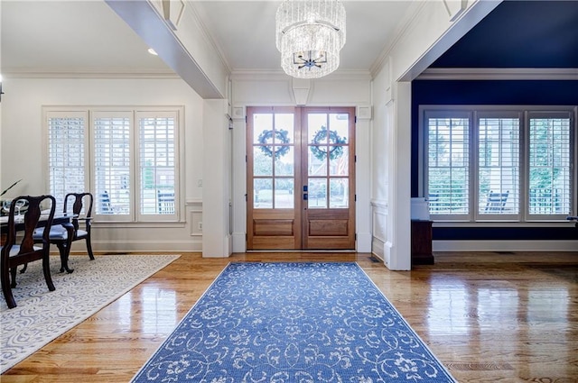 foyer featuring french doors, an inviting chandelier, a wealth of natural light, and crown molding