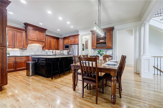 kitchen featuring light wood-type flooring, tasteful backsplash, ornate columns, and a kitchen island