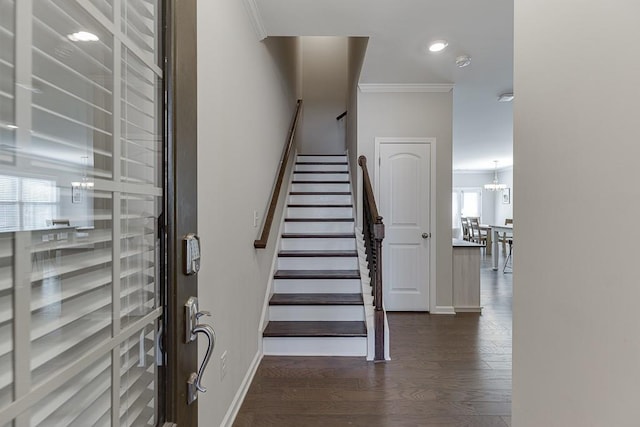 stairway featuring a notable chandelier, baseboards, crown molding, and wood finished floors