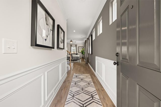 hall with light hardwood / wood-style floors and crown molding