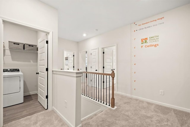 corridor with washer / clothes dryer and light carpet