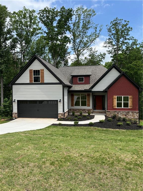 view of front facade with stone siding, driveway, a garage, and a front yard