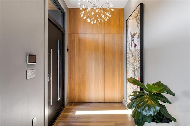 hallway with wood finished floors and a chandelier