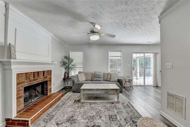 5385 Spotted Fawn Ct, Suwanee, GA 30024 - living room with wood finished floors, ceiling fan, a textured ceiling, a brick fireplace, and ornamental molding