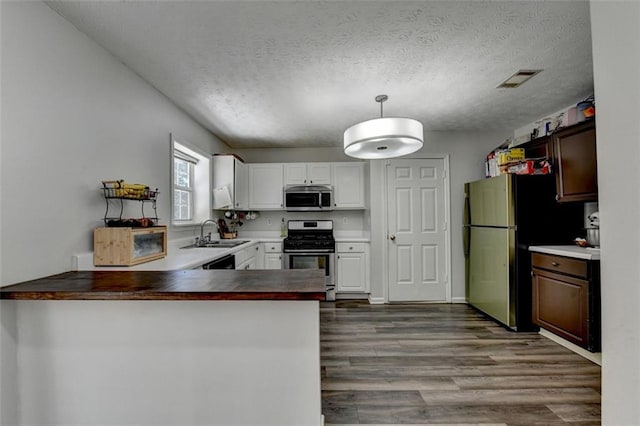 5385 Spotted Fawn Ct, Suwanee, GA 30024 - kitchen featuring appliances with stainless steel finishes, dark wood-style flooring, a peninsula, white cabinets, and a textured ceiling