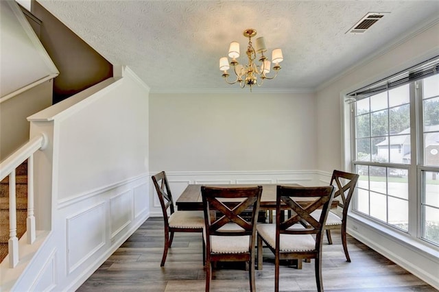 5385 Spotted Fawn Ct, Suwanee, GA 30024 - dining room featuring a chandelier, a textured ceiling, dark wood finished floors, a wainscoted wall, and a decorative wall