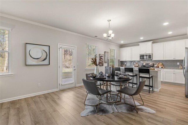 dining space featuring ceiling fan with notable chandelier, light hardwood / wood-style floors, and crown molding