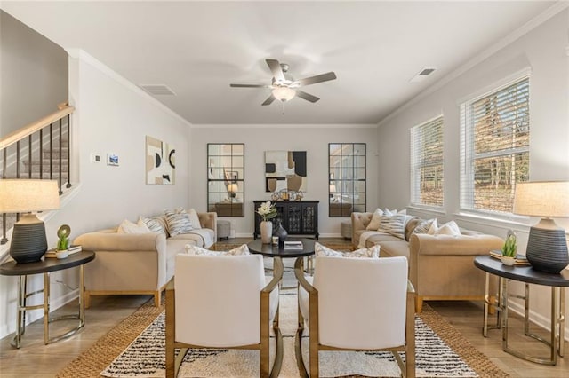 living room featuring light wood-type flooring, ceiling fan, crown molding, and a healthy amount of sunlight