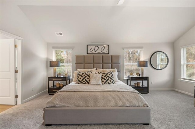 bedroom with lofted ceiling, light colored carpet, ceiling fan, and multiple windows