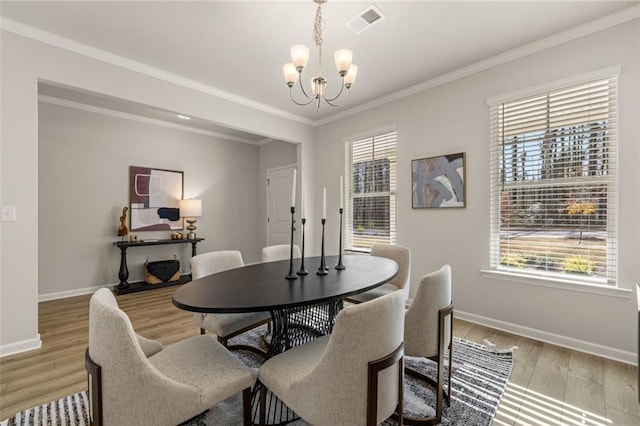 dining space with ornamental molding, light hardwood / wood-style floors, and a notable chandelier