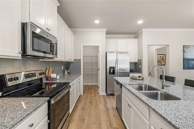 kitchen featuring stainless steel appliances, white cabinets, sink, and an island with sink