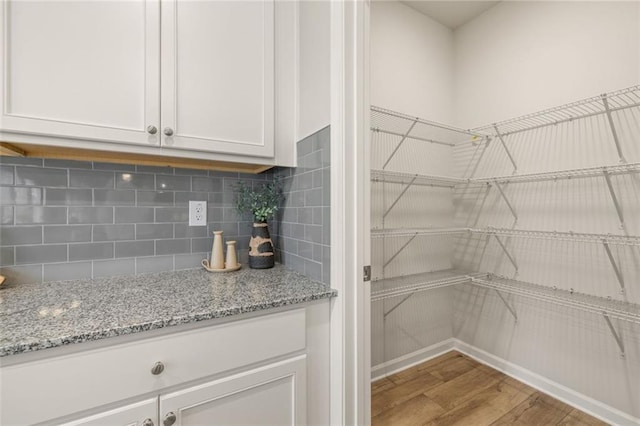 kitchen with white cabinets, stainless steel appliances, light stone countertops, decorative backsplash, and sink