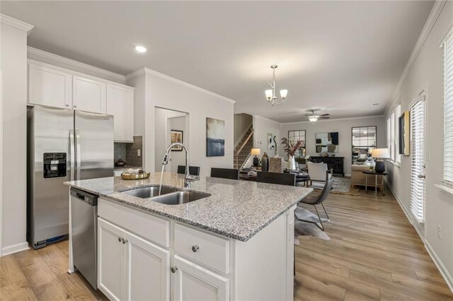 kitchen featuring sink, stainless steel appliances, white cabinets, and light stone counters