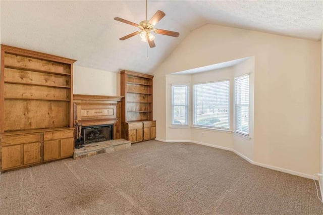 unfurnished living room with lofted ceiling, a fireplace with raised hearth, a textured ceiling, carpet flooring, and baseboards