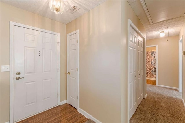 foyer entrance with visible vents, a textured ceiling, and baseboards