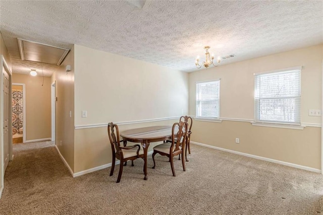 dining area with a textured ceiling, attic access, baseboards, and carpet floors