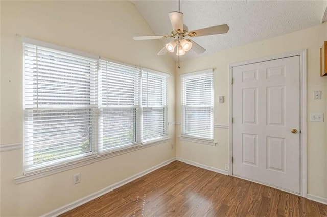 entrance foyer with a textured ceiling, wood finished floors, baseboards, ceiling fan, and vaulted ceiling