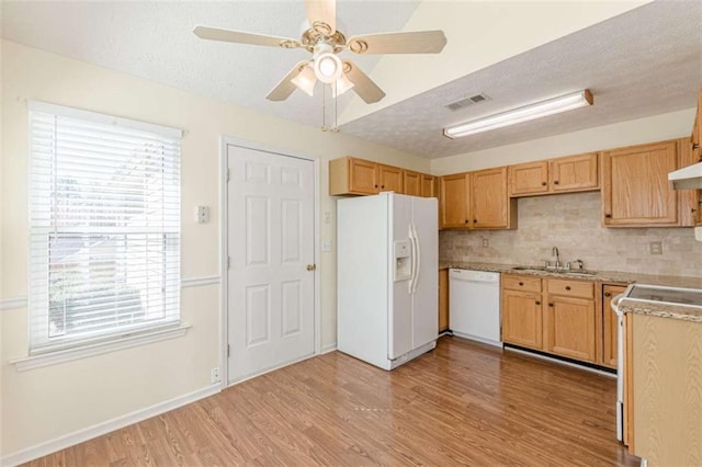 kitchen featuring visible vents, light wood-style flooring, a sink, backsplash, and white appliances