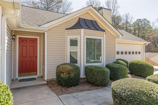 doorway to property with a garage, a standing seam roof, a chimney, and a shingled roof