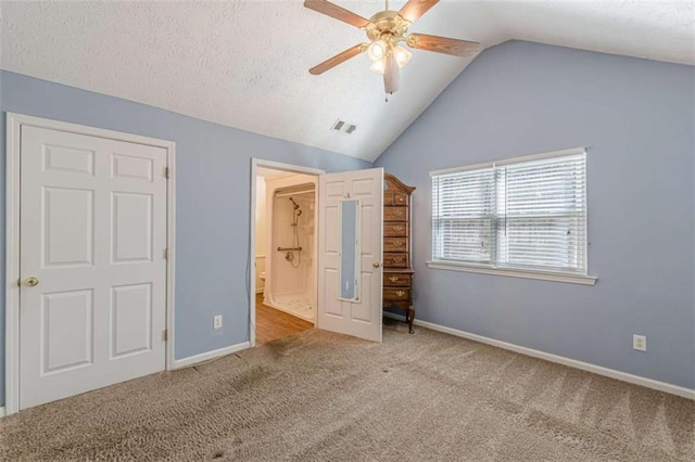 unfurnished bedroom featuring baseboards, visible vents, vaulted ceiling, a textured ceiling, and carpet flooring