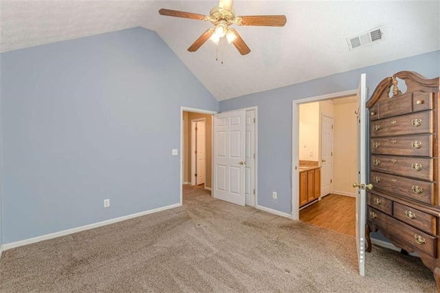 unfurnished bedroom with visible vents, a textured ceiling, carpet flooring, baseboards, and vaulted ceiling