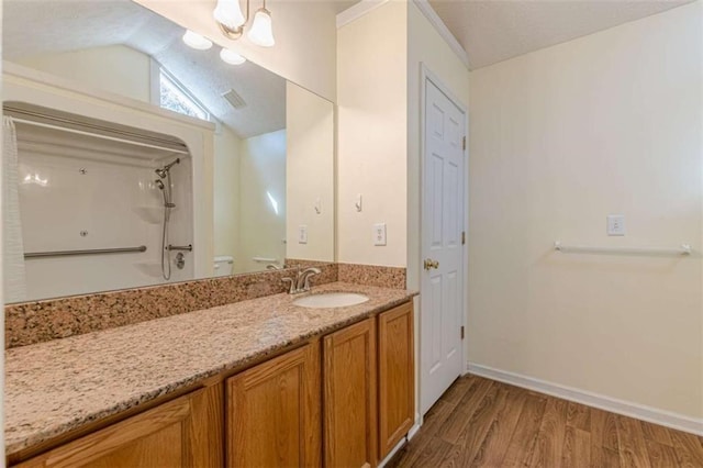 bathroom featuring a notable chandelier, lofted ceiling, wood finished floors, baseboards, and vanity