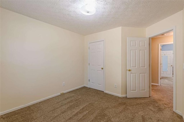 unfurnished bedroom with a textured ceiling, baseboards, and carpet floors