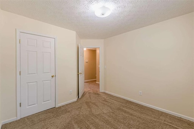 unfurnished bedroom featuring baseboards, carpet floors, and a textured ceiling