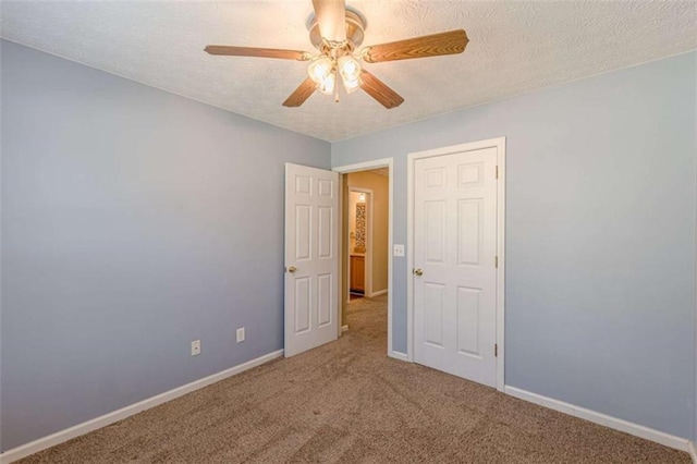 carpeted empty room with a textured ceiling, baseboards, and a ceiling fan