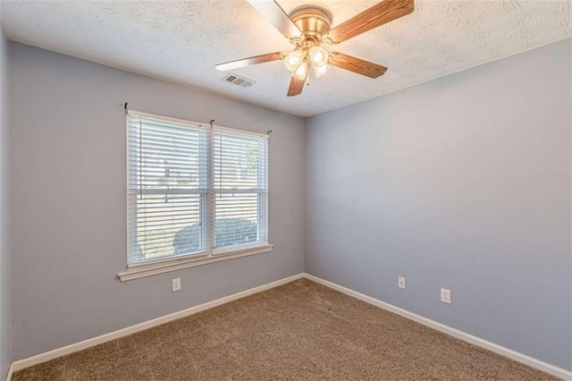 carpeted empty room with a ceiling fan, baseboards, visible vents, and a textured ceiling