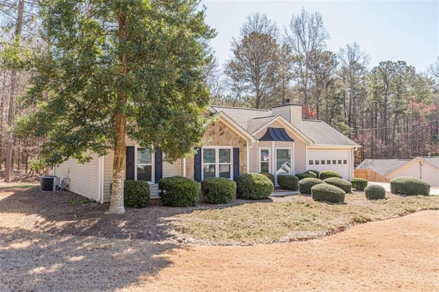 view of front of house featuring cooling unit, an attached garage, and a chimney