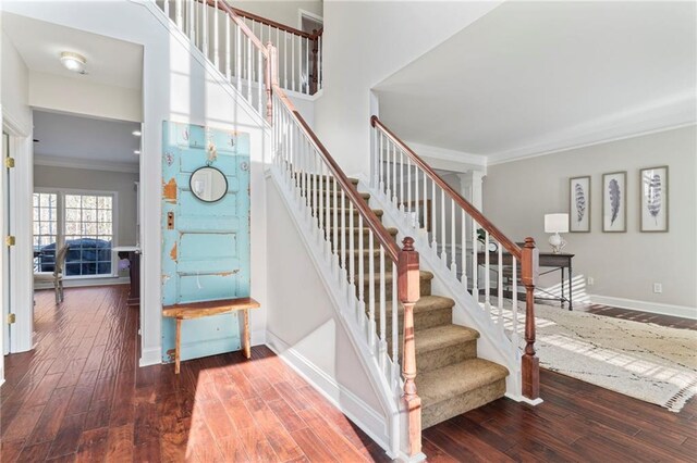 stairs featuring crown molding, a towering ceiling, and hardwood / wood-style flooring