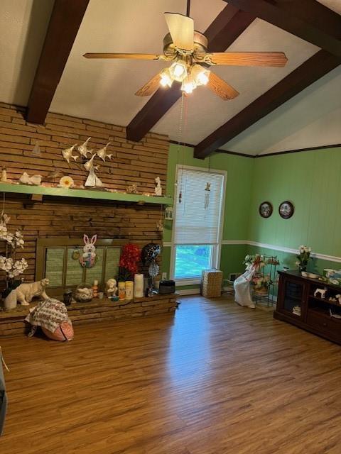 living room with a ceiling fan, lofted ceiling with beams, and wood finished floors