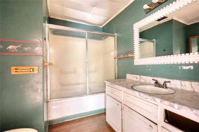 full bathroom featuring large vanity, crown molding, toilet, wood-type flooring, and shower / bath combination with glass door