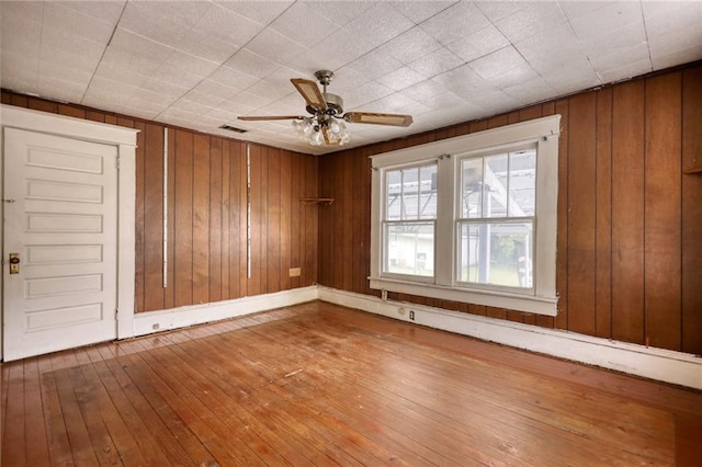 spare room with wood walls, light hardwood / wood-style floors, and ceiling fan