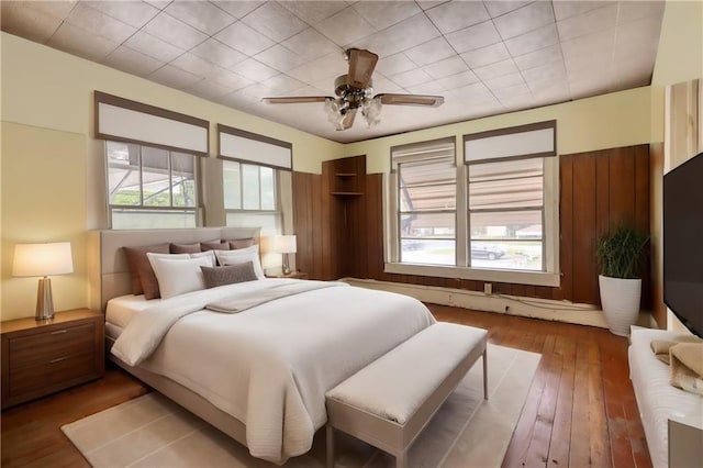 bedroom featuring ceiling fan, hardwood / wood-style floors, and multiple windows