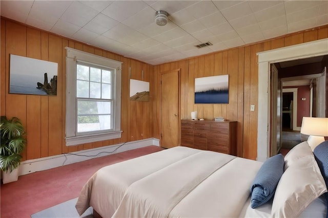 carpeted bedroom with wood walls