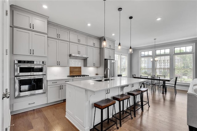 3108 Huntington Pl, Milton, GA 30004 - kitchen featuring appliances with stainless steel finishes, a sink, backsplash, a kitchen bar, and a kitchen island with sink