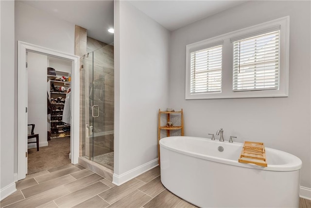 3108 Huntington Pl, Milton, GA 30004 - bathroom with baseboards, a freestanding tub, a stall shower, a spacious closet, and wood finish floors
