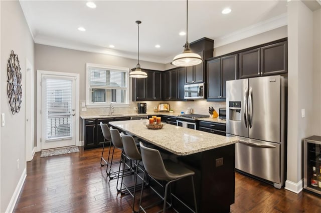 kitchen with decorative backsplash, light stone counters, a center island, stainless steel appliances, and a sink