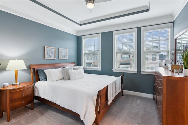 bedroom featuring carpet floors, baseboards, a raised ceiling, and crown molding