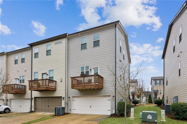 rear view of property with a garage, concrete driveway, and central air condition unit