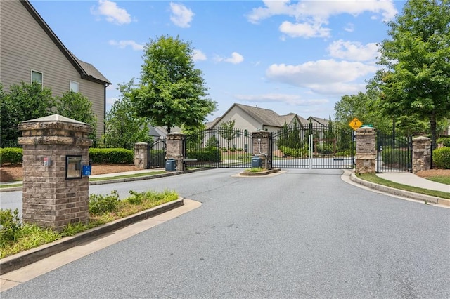 view of street with a gated entry, sidewalks, and a gate