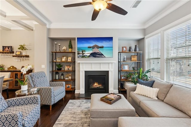 living area with crown molding, visible vents, a fireplace with flush hearth, a ceiling fan, and wood finished floors