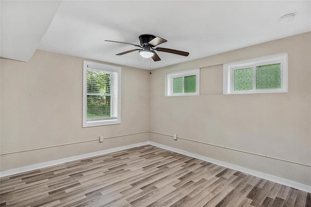 spare room with light wood-style floors, baseboards, and a ceiling fan