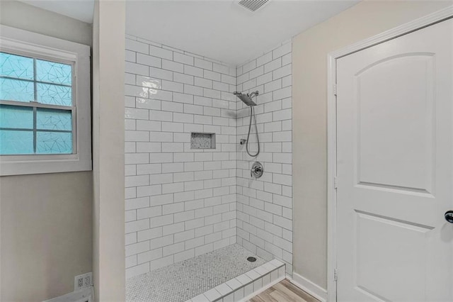 bathroom with a stall shower, wood finished floors, visible vents, and baseboards